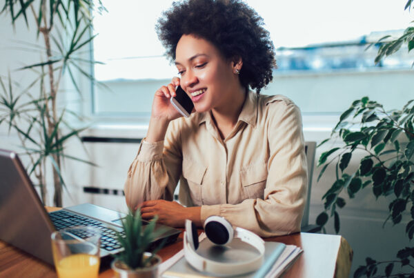 Smiling lady on the phone at a desk with laptop