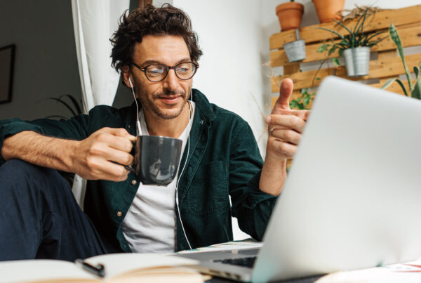 Man with glasses and coffee working on a laptop