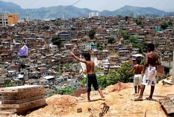 Three boys in Brazil flying kites above the favelas