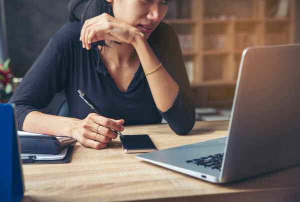 Lady with pen and phone working on a laptop