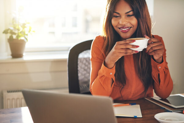 Lady drinking coffee looking at her laptop