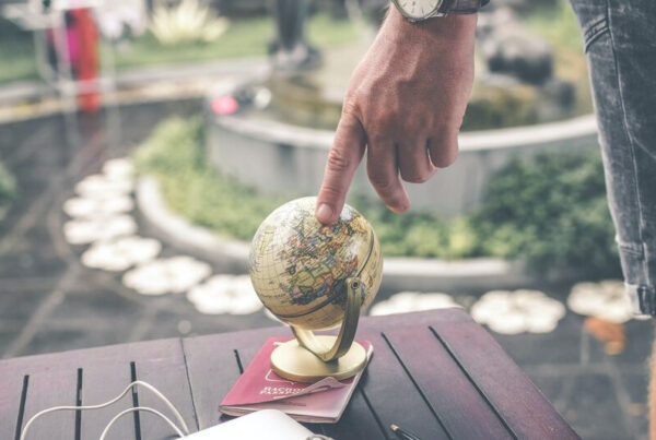 man with his finger on a small globe