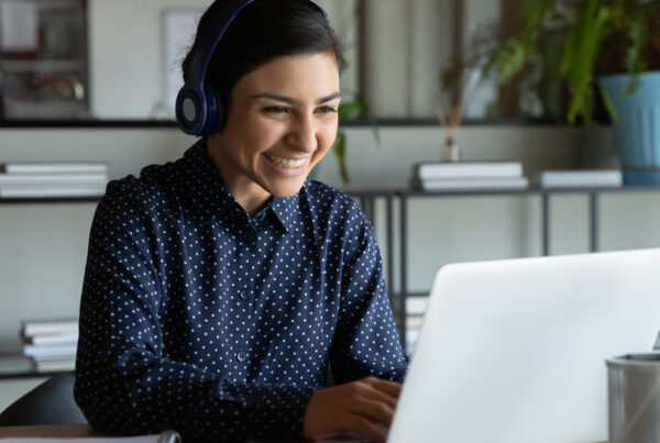 Smiling lady with headphones on a laptop