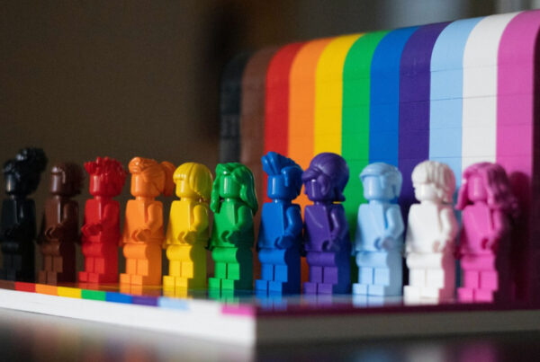 Eleven Lego monochrome minifigures against rainbow backdrop