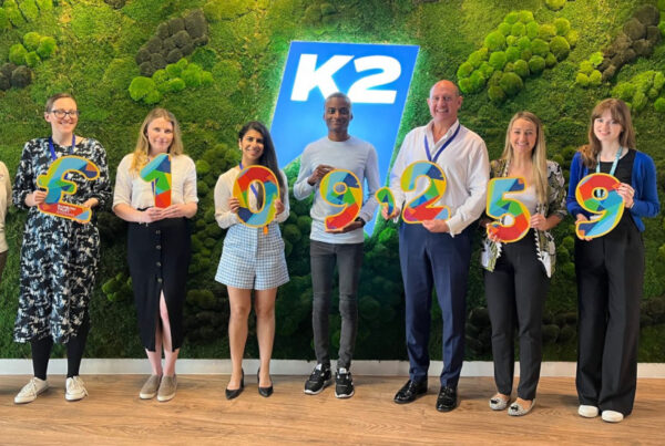 K2 team standing front of the K2 logo