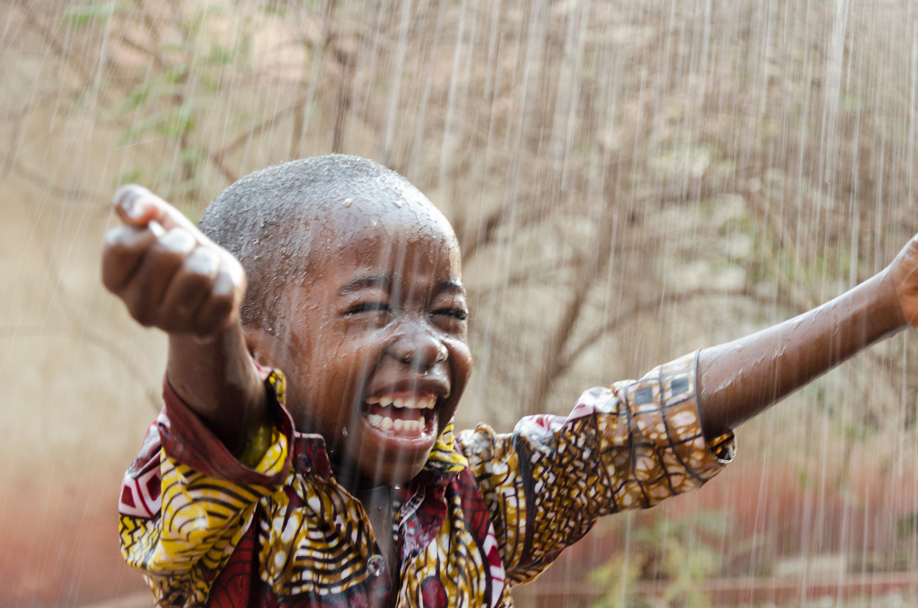 Laughing little boy in the rain