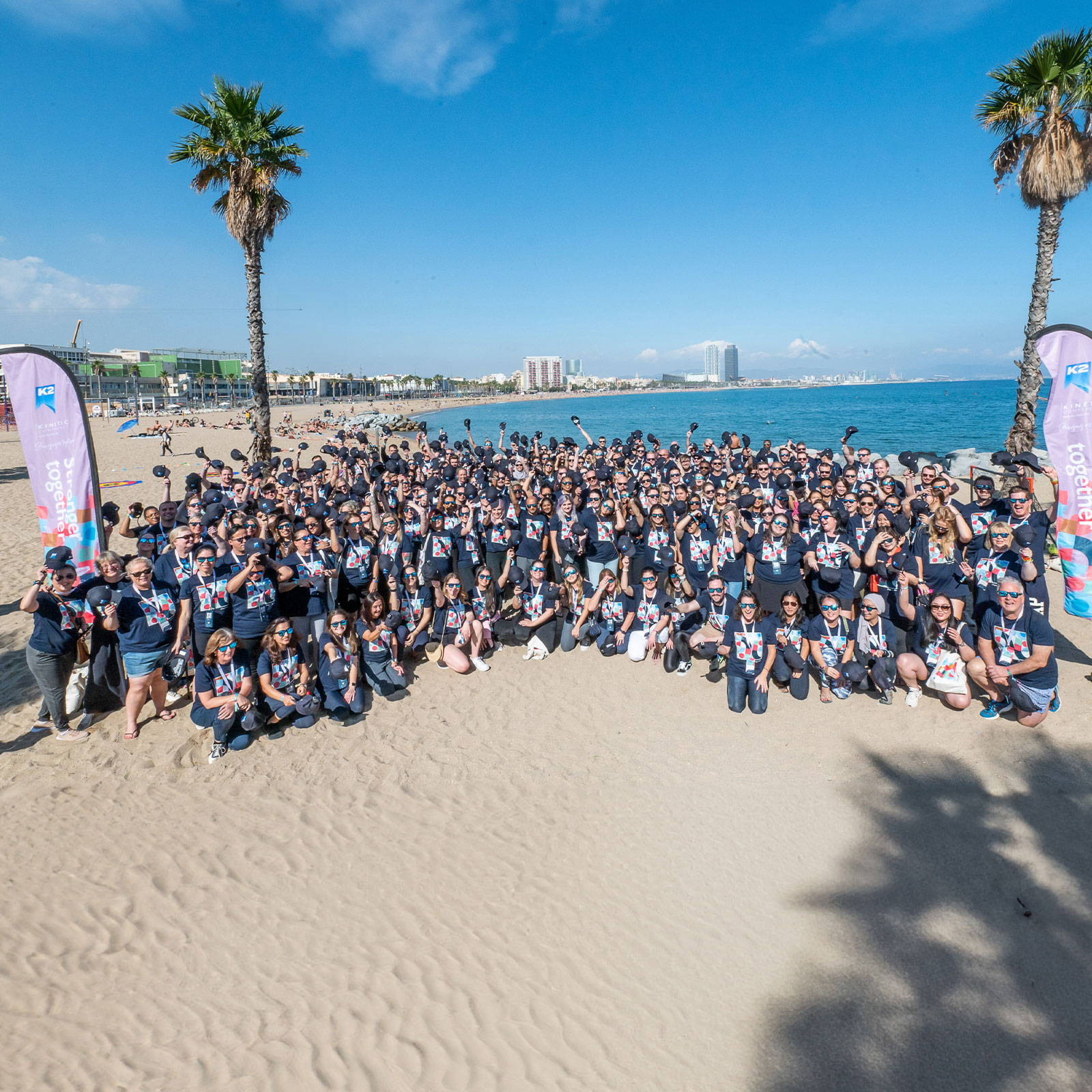 K2 team on Barcelona beach smiling throwing hats