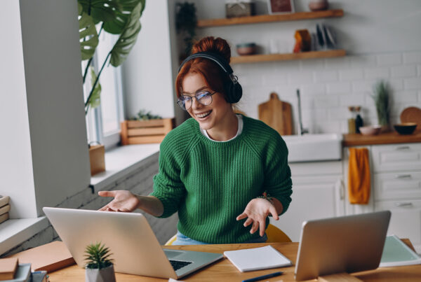 Smiling lady with headphones at a desk with laptop